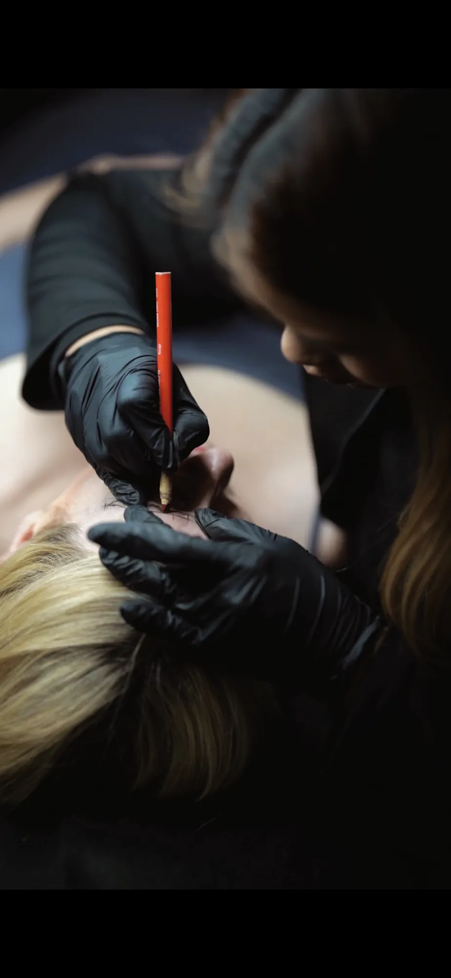 Kim Vo zeichnet die Brauenkontur mit sterilen Handschuhen vor